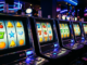 Rad av upplysta spelautomater med färgglada symboler i en mörk casinomiljö, som symboliserar nätcasino.
